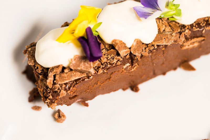 Close up of brownie slice with cream and flowers from The King's Wark Dessert menu